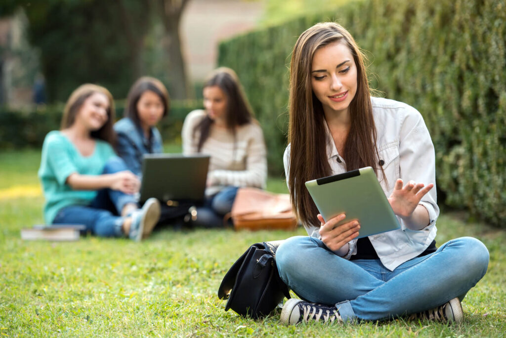 Portrait of a smiling college girl is holding tablet PC.